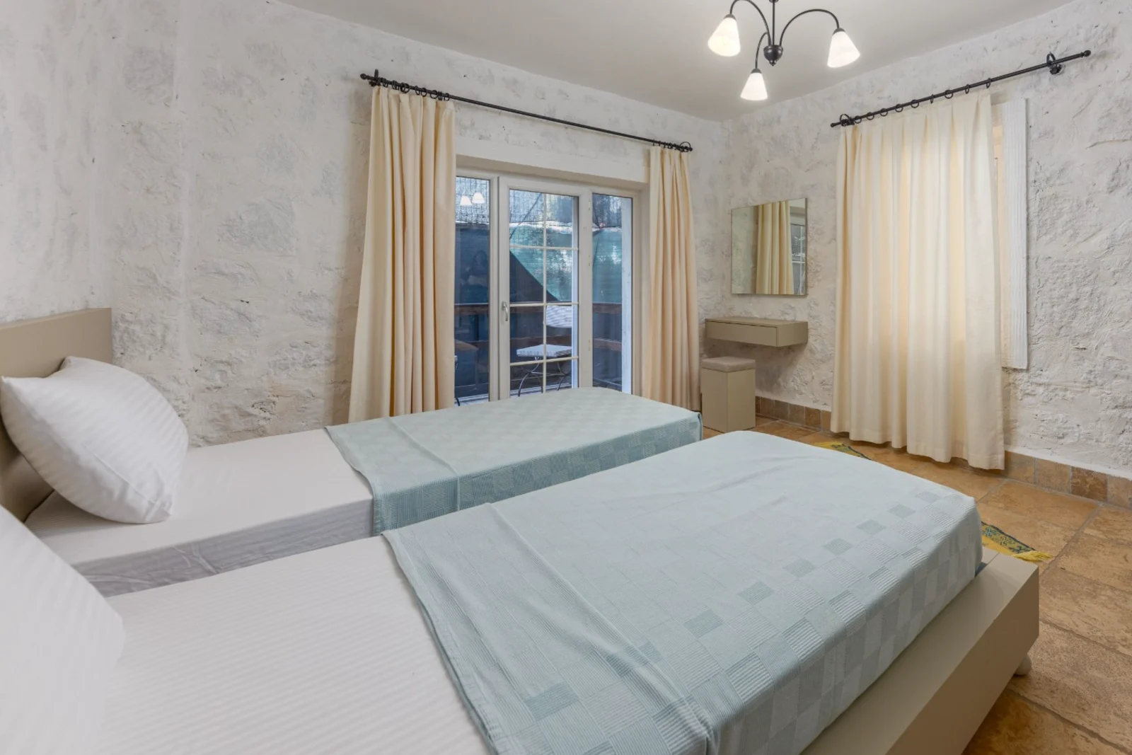 Chambre meublée prête à recevoir, murs en pierre chaulée et sol en terre cuite